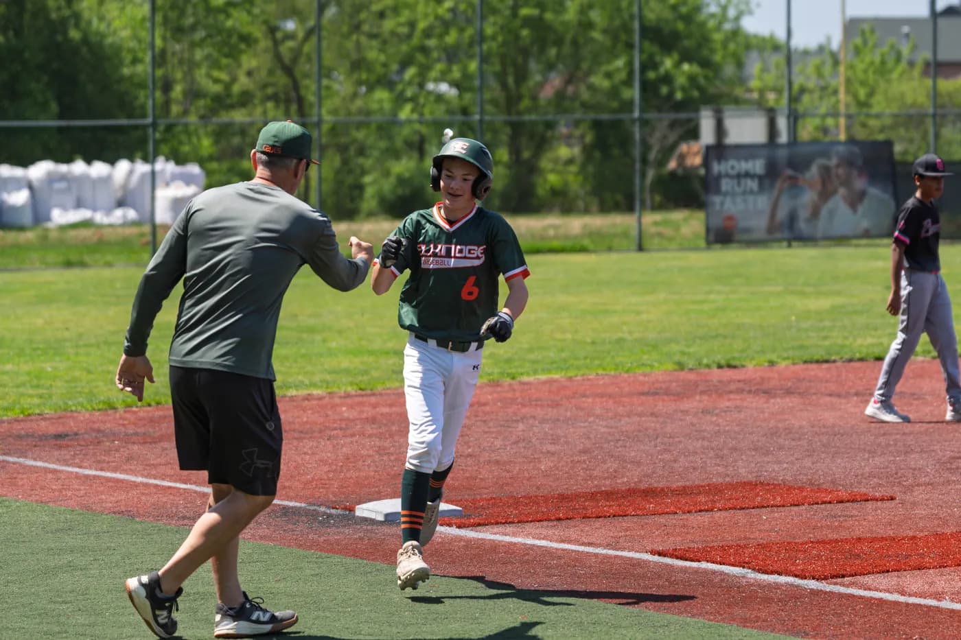 A coach greets a Hurricanes runner with a fist bump as he rounds the bases